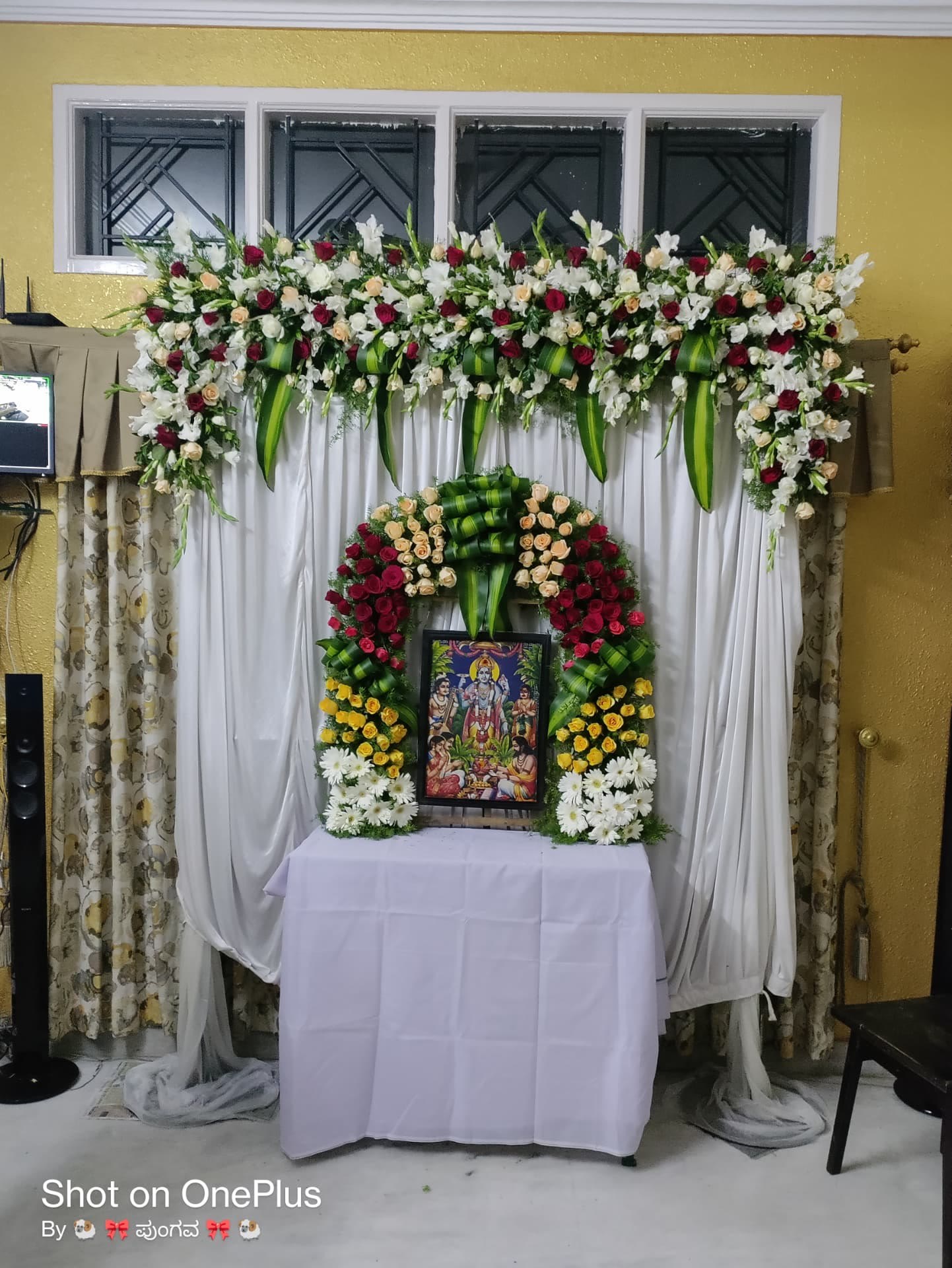 Home pooja photo frame decorated with roses, lilies and gerberas