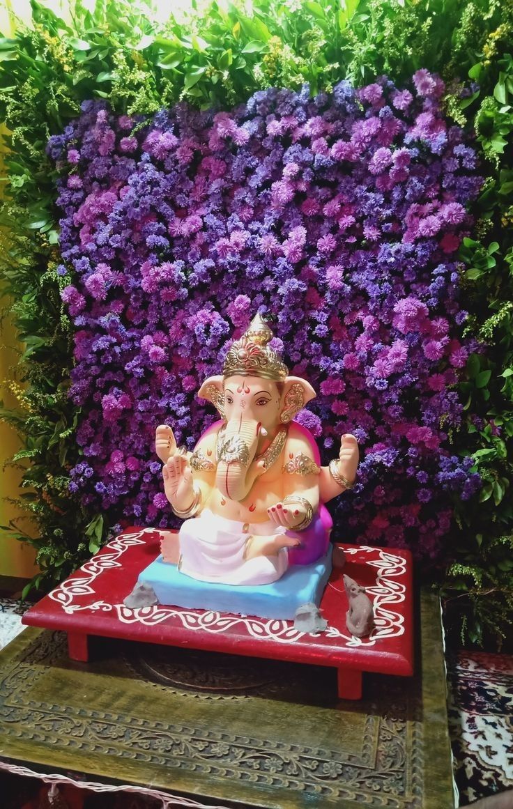 SF-04 — Ganesha idol with purple flower and green leaf wall backdrop