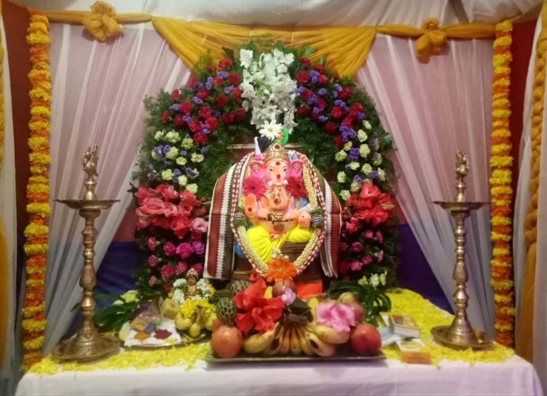 Ganesha pandal decoration with flower arch and brass lamps