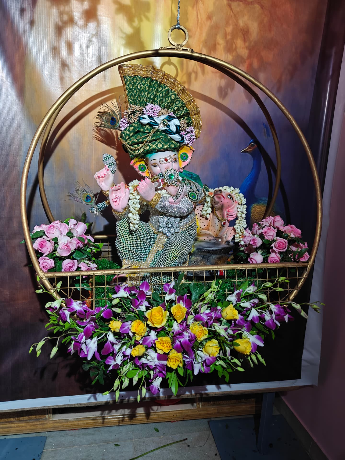 Ganesha idol decorated in a gold ring with roses and orchids