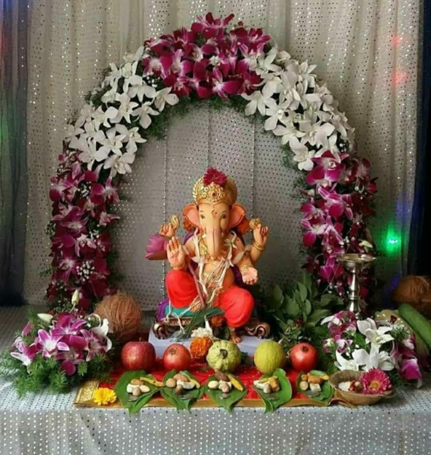 Ganesha idol under a purple orchid and white lily flower arch