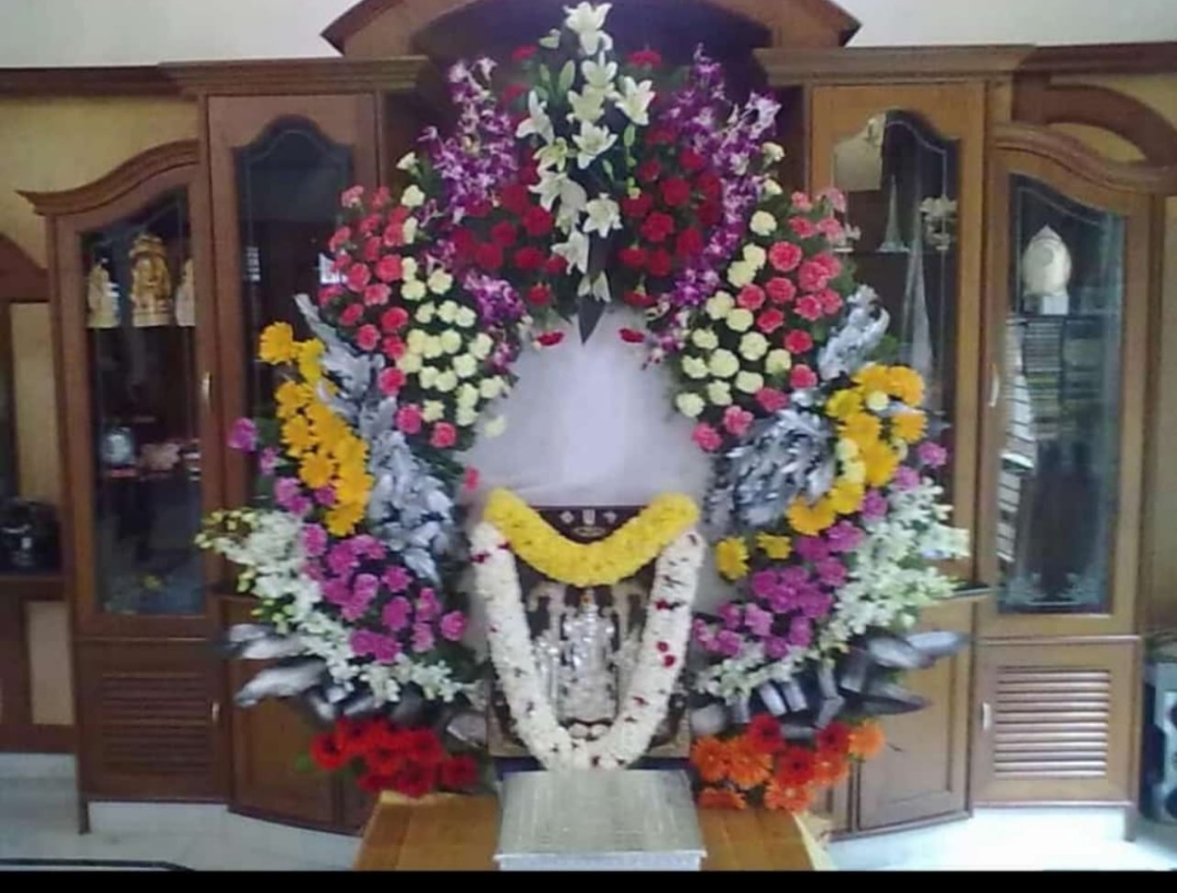 Traditional home pooja decoration with garlands and flower arch